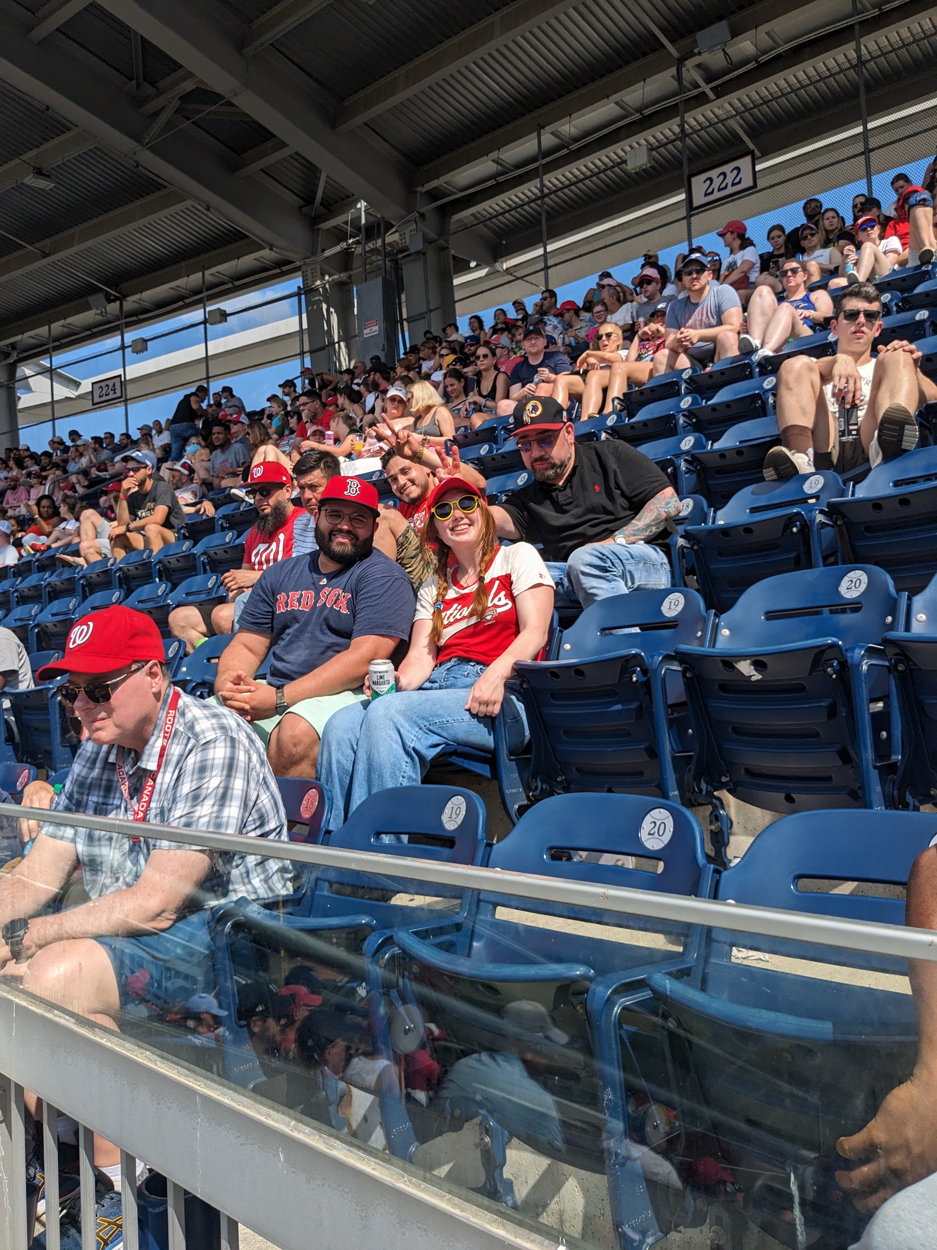 photo of two people seated in baseball clothing and people behind them making rabbit ears